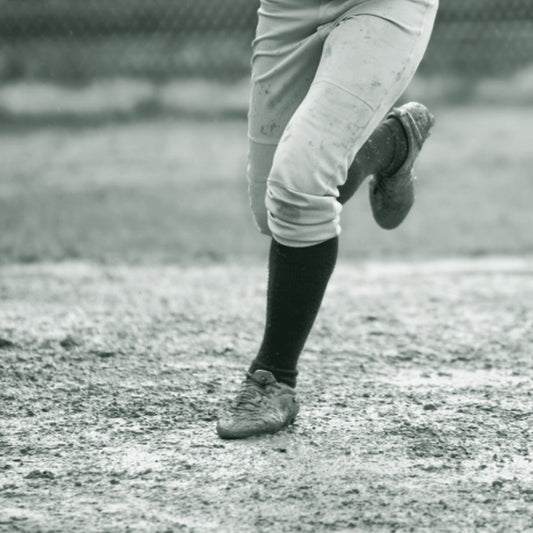 Softball player in white and red uniform pants sliding into base, ThreaderPros custom softball pants